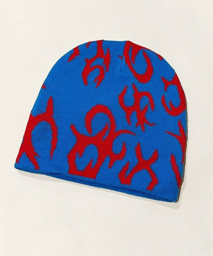 a blue and red beanie with symbols on it sitting on top of a white surface