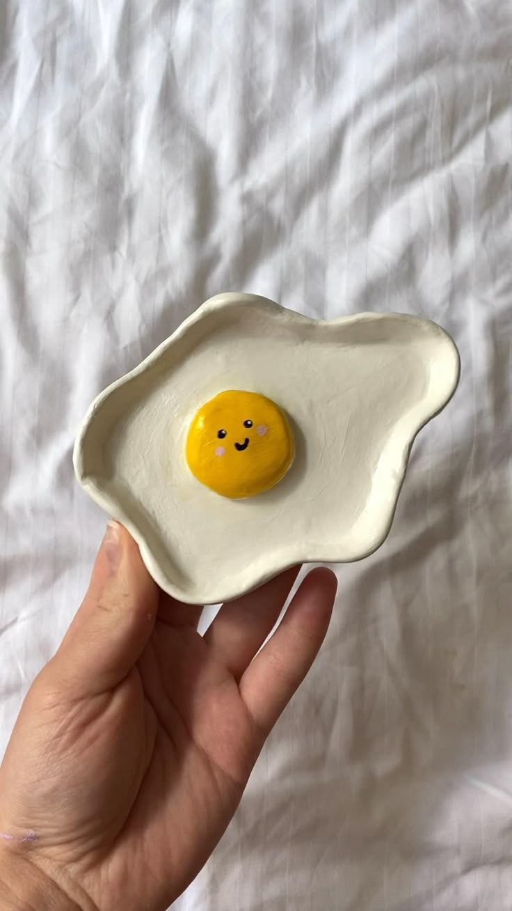 a hand holding an egg shell with a smiley face painted on it's side