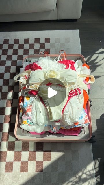 a suitcase with clothes on it sitting on the floor next to a checkered rug