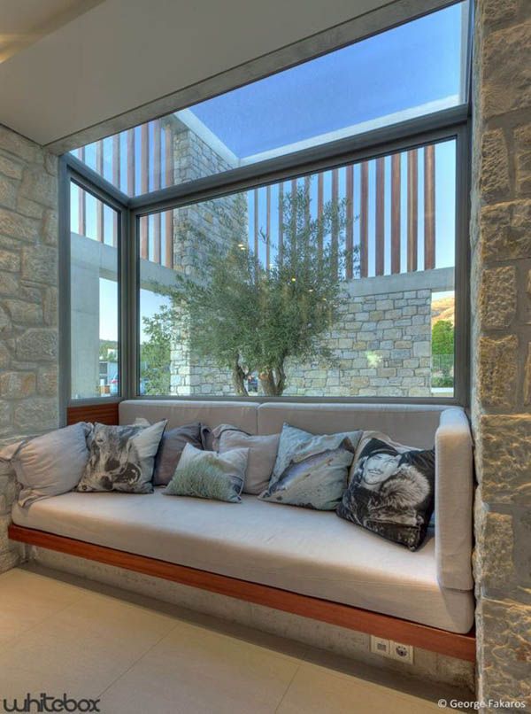 a white couch sitting under a window next to a stone wall