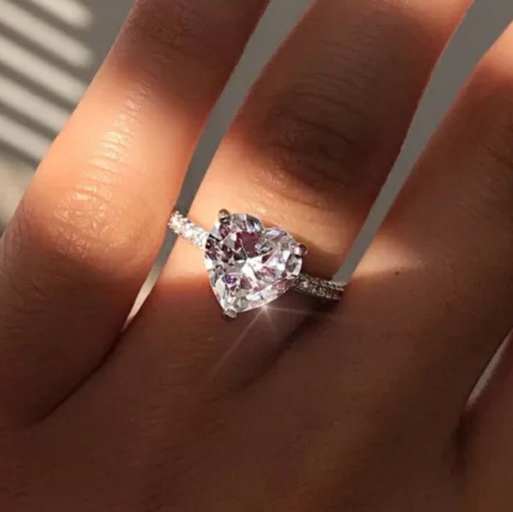 a woman's hand with a diamond ring on top of her finger and an engagement band