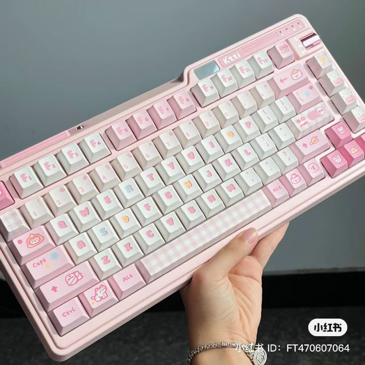 a hand holding a pink and white keyboard