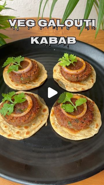 four flatbreads on a black plate with garnishes and green leaves