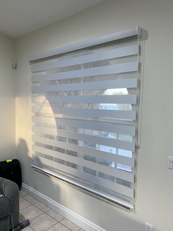 a living room with a gray couch and white blinds