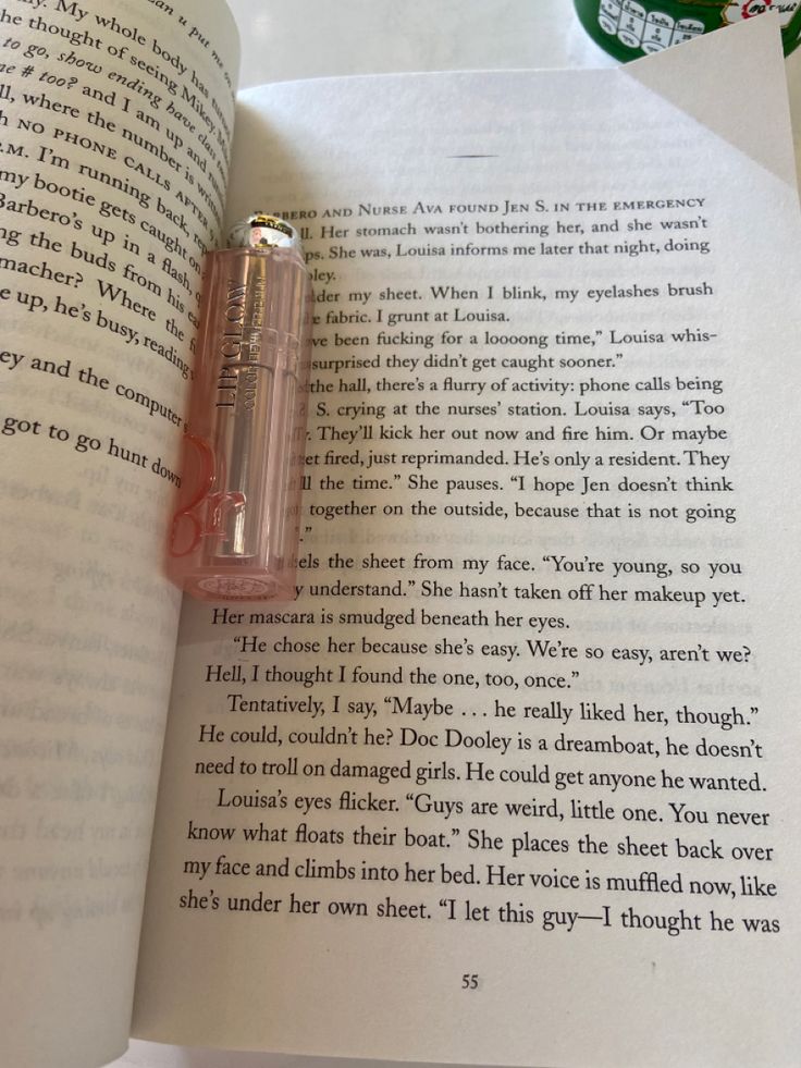 an open book with a pink pen resting on top of it