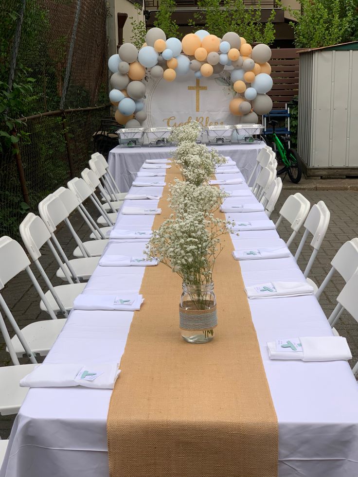 a long table set up with flowers and balloons