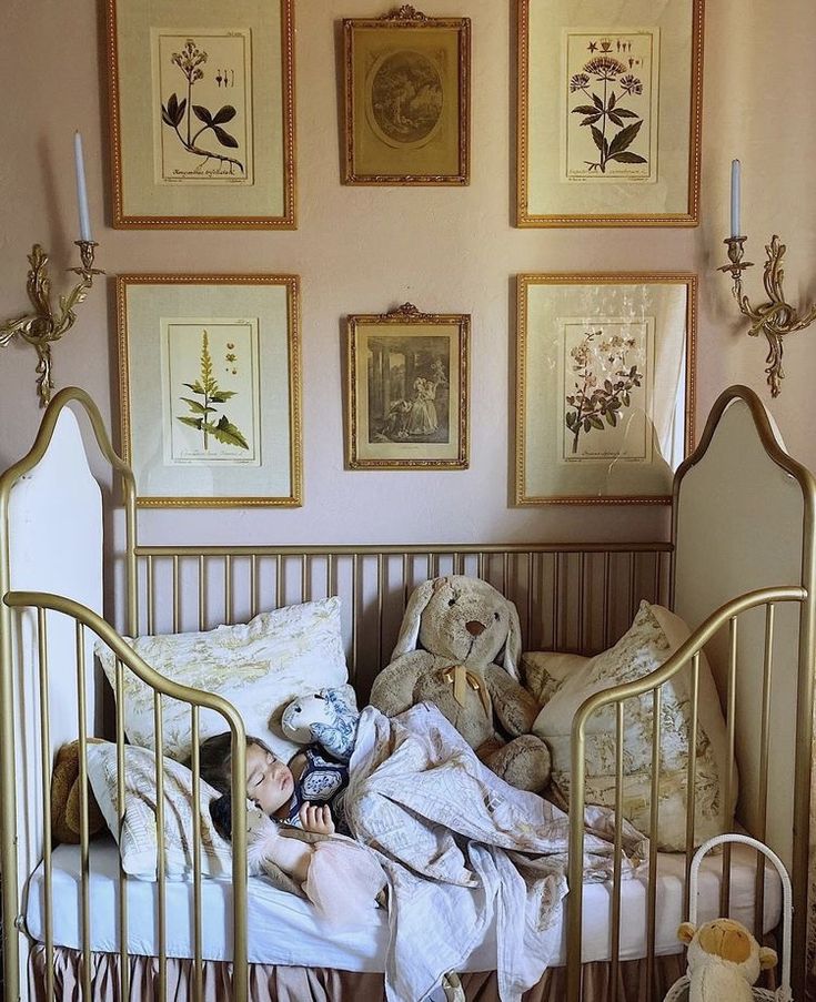 a baby in a crib with stuffed animals on the bed and pictures above it