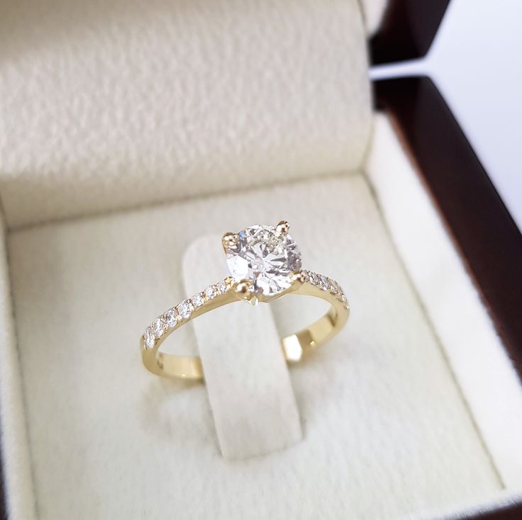 an engagement ring in a box with its lid open and the diamond set on it's side