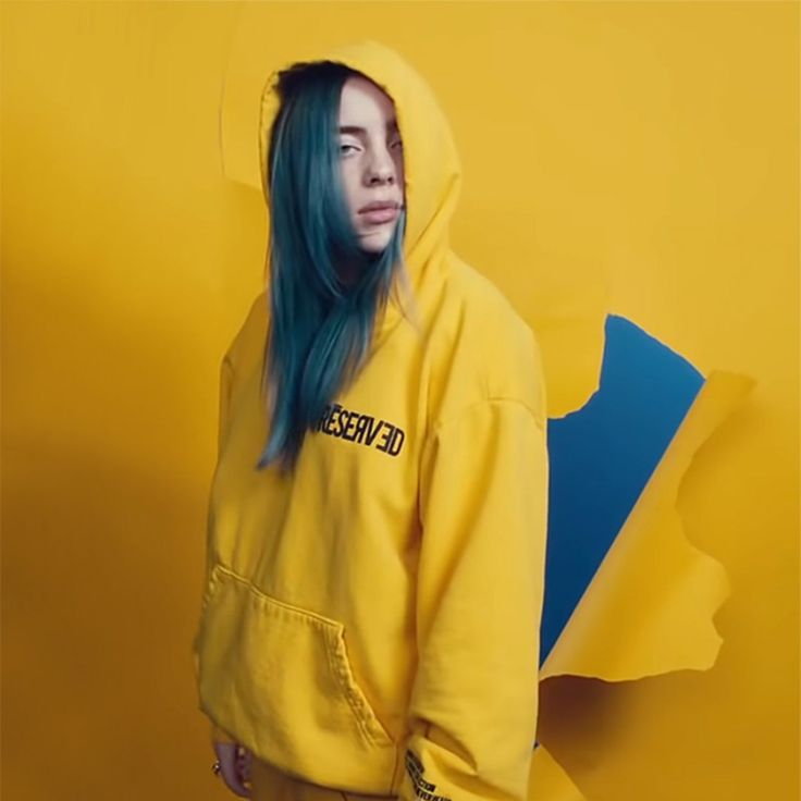 a woman with blue hair wearing a yellow hoodie