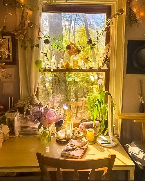 a table with plates and cups on it in front of a window filled with flowers