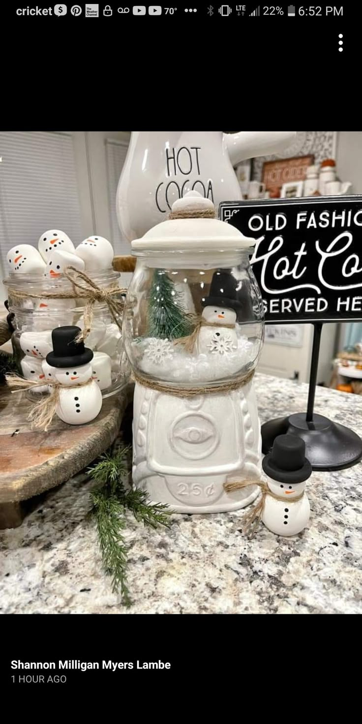 there are many snowmen in the glass jar on this counter top, and one has a sign that says old fashion festive served here