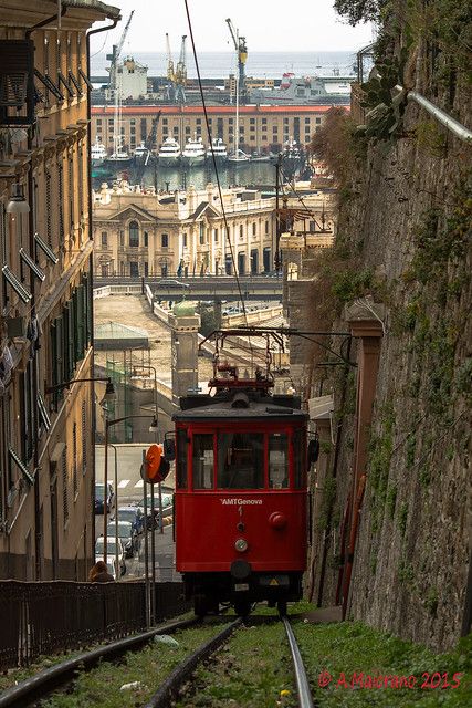 a red trolley car going down the tracks in an urban area with buildings on either side