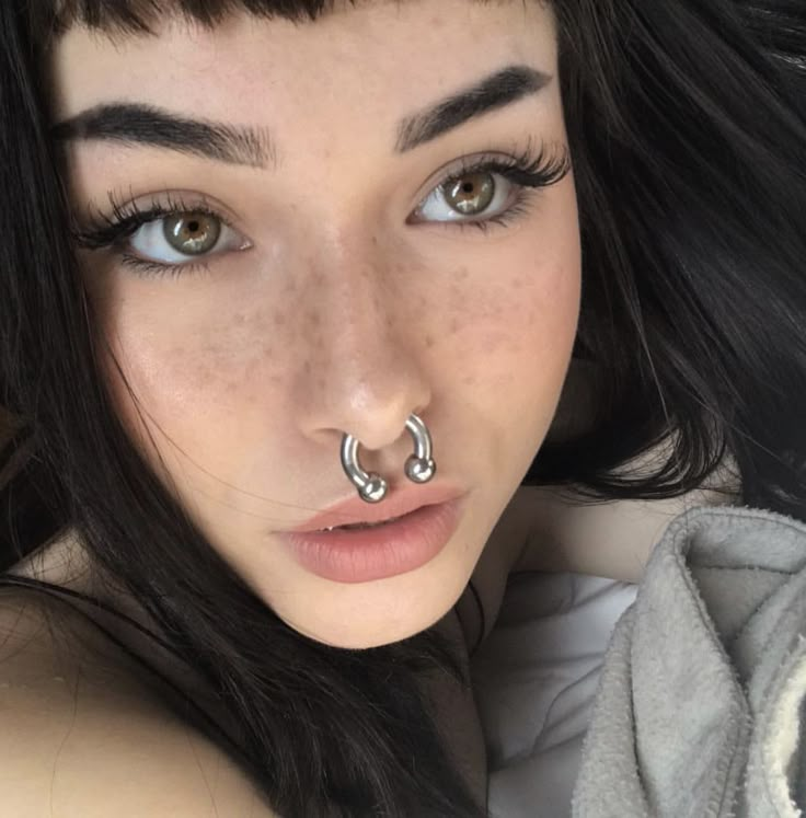 a close up of a person with a nose ring on her nose and piercing in the middle