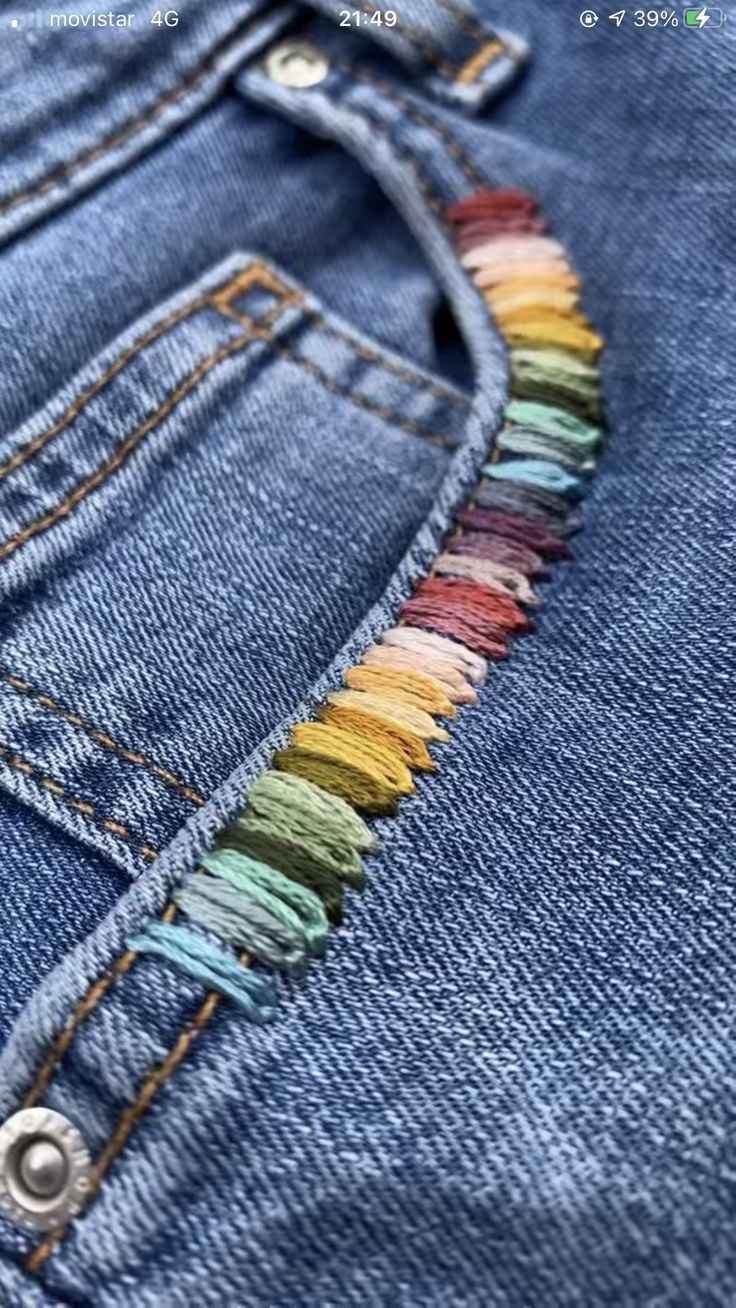 the back pocket of a pair of blue jeans with multicolored fringes on it