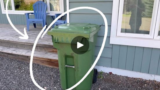 a green trash can sitting in front of a house