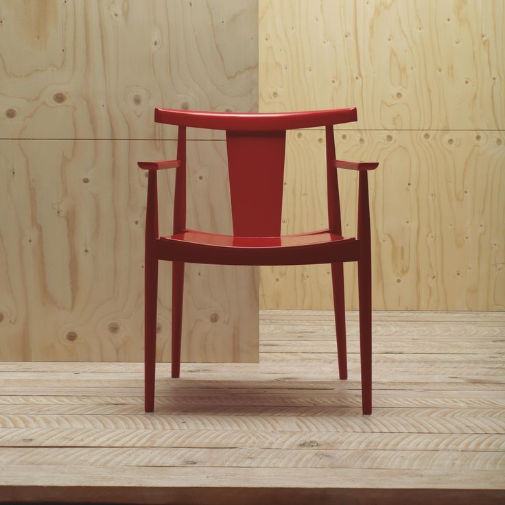 a red chair sitting on top of a hard wood floor next to a wooden wall