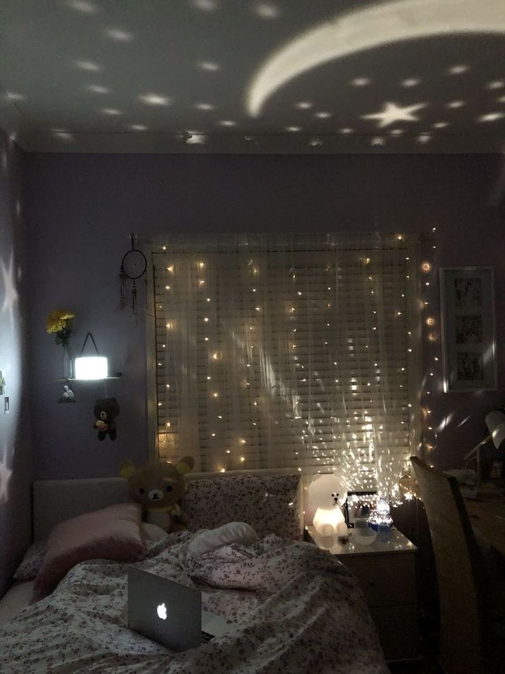 a laptop computer sitting on top of a bed next to a window covered in lights