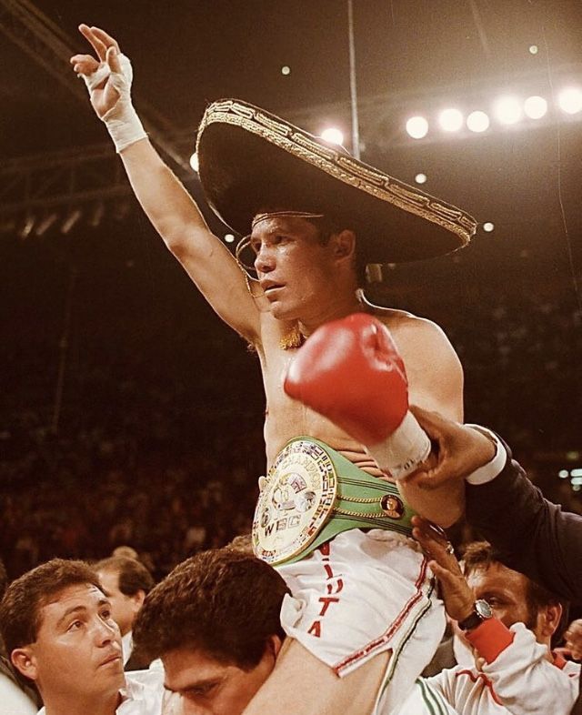 a man with a red boxing glove on his head in the middle of a crowd