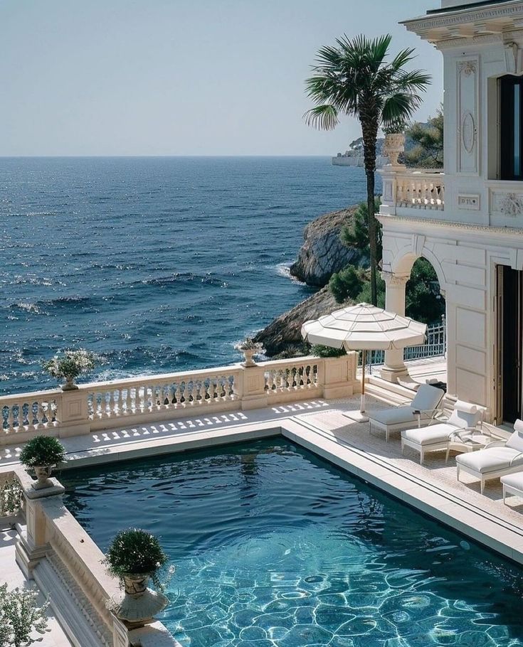 an outdoor swimming pool with chaise lounges next to the ocean