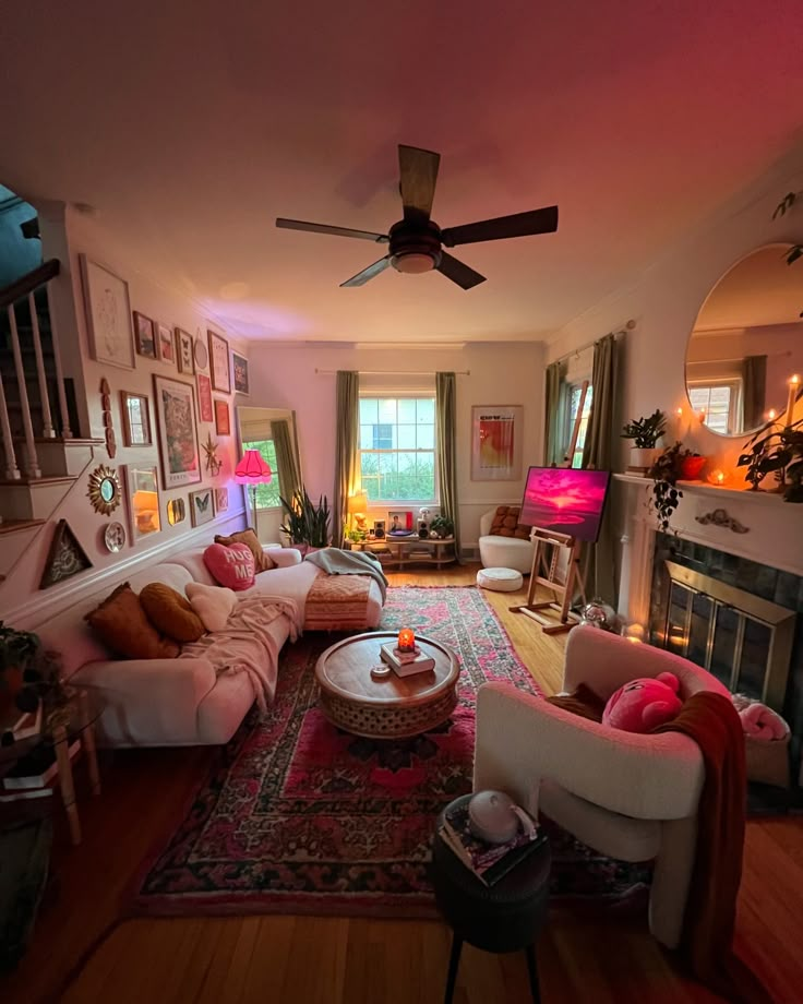 a living room filled with furniture and a fire place under a ceiling fan on top of a hard wood floor