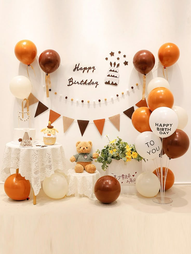 a birthday party with balloons, cake and teddy bear on the table in front of it