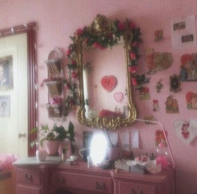 a room with pink walls and lots of decorations on the wall, including a mirror