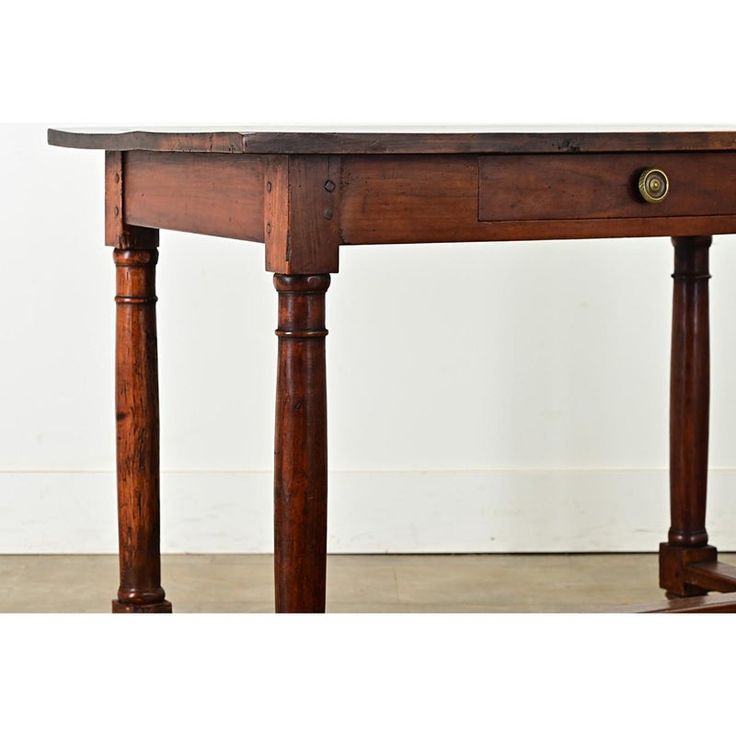 an old wooden table with two legs and a drawer on the top, against a white wall