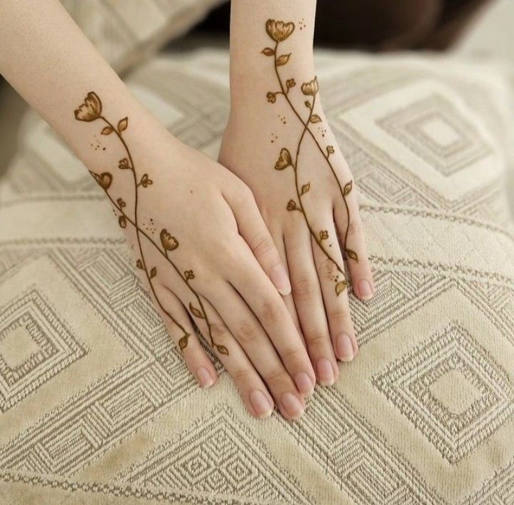 two hands holding each other with tattoos on their palms and fingers, both decorated with flowers