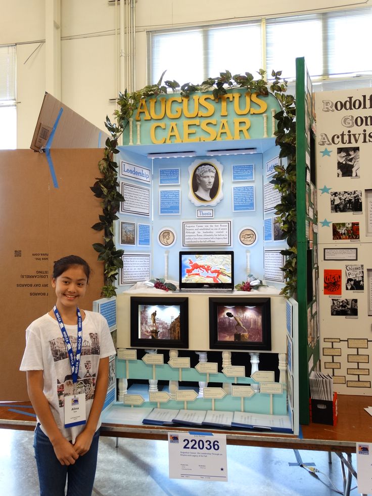 a young boy standing next to a model of a ceasar exhibit booth at a science fair