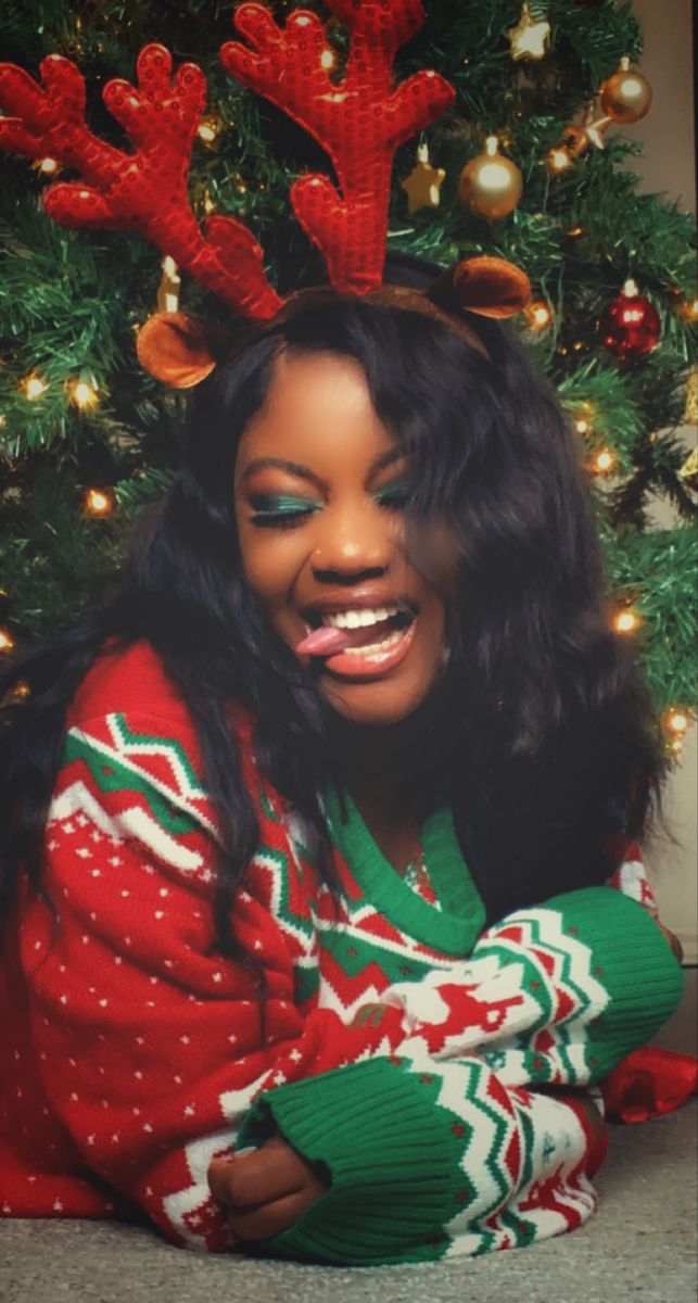 a woman in a red and green christmas sweater with reindeer antlers on her head