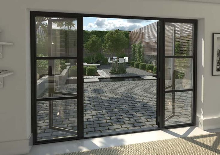 an empty room with two large windows and brick flooring on the outside, looking out onto a courtyard