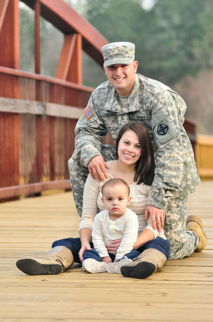 a soldier poses for a photo with his wife and baby