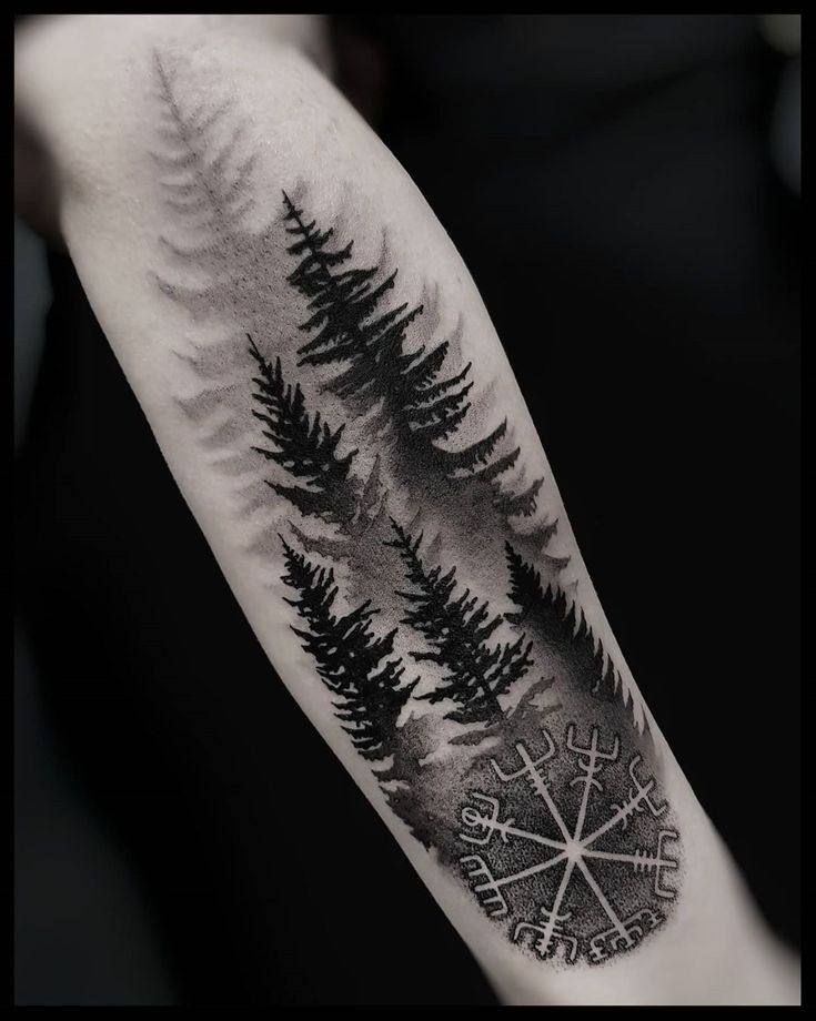 a black and white photo of a forest with compass tattoo on the arm, done by person