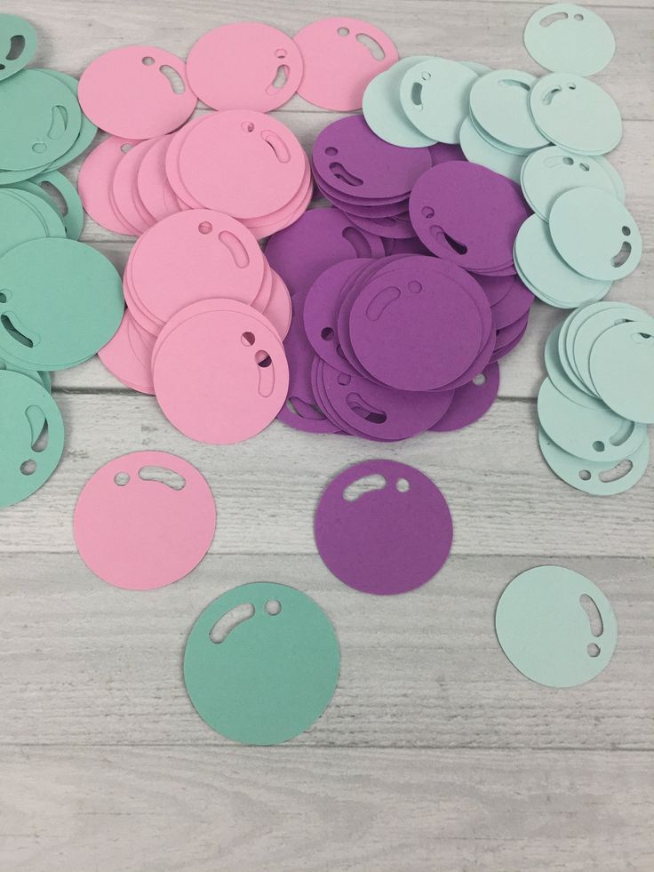 some pink and blue paper cut outs on a wooden table with one missing the hole