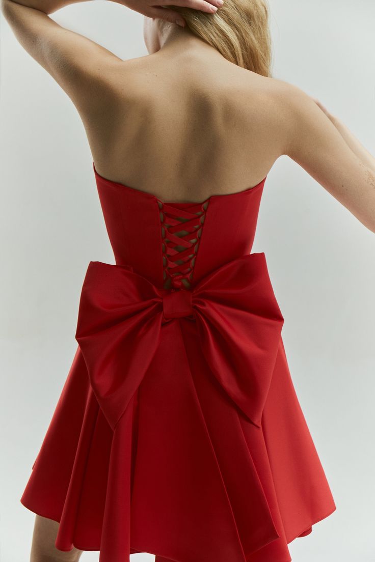 Introducing the Emily Dress with Bow: a stunning mini satin dress in a vibrant red color, designed to make a bold statement. This eye-catching dress features a dramatic maxi bow at the lower back, perfect for girls who love to stand out and make an impression. The Emily Dress is not only striking in design but also offers a perfect fit with adjustable lacing at the back. This ensures that you feel comfortable and confident throughout any special event. The vibrant red hue enhances its sophistica Formal A-line Dress With Satin Bow, Formal A-line Mini Dress With Bow Tie Back, Elegant A-line Mini Dress With Satin Bow, Sleeveless Evening Dress With Bow, Evening Mini Dress With Detachable Bow, Sleeveless, Party Satin Midi Dress With Corset Back, A-line Dresses With Bow For Gala, Satin A-line Dress With Bow, Satin Midi Dress With Corset Back For Party