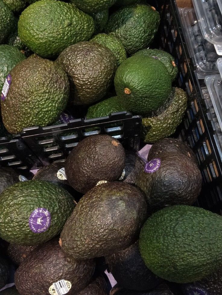 several avocados are stacked up in a basket at the grocery store and ready to be sold