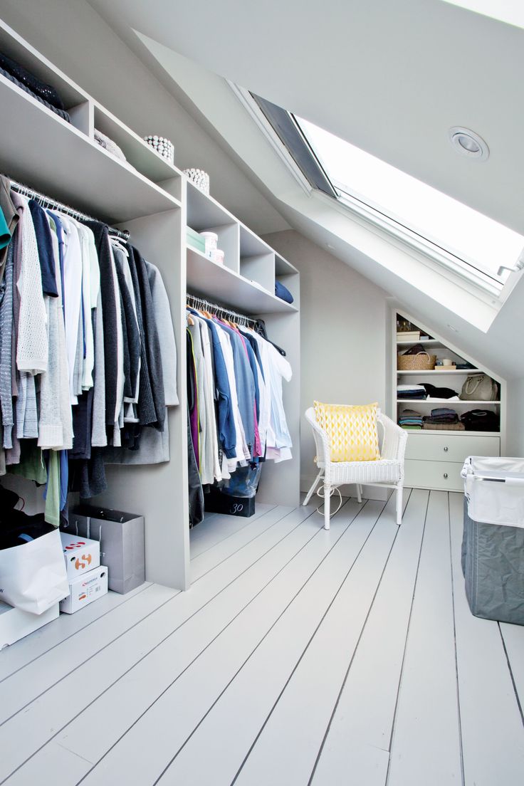 an attic bedroom with lots of closet space and clothes on hangers in the corner