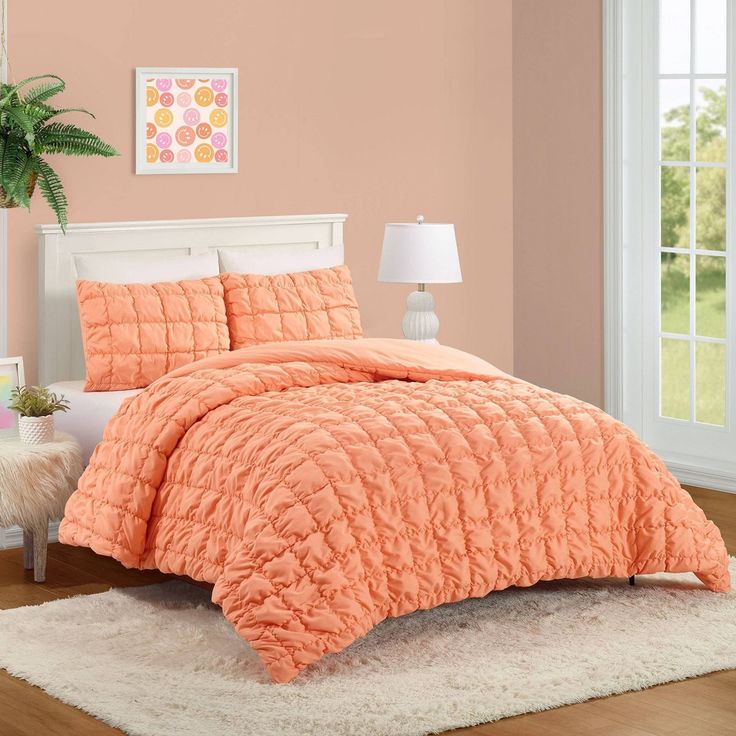 an orange comforter set on a bed in a room with pink walls and white rugs