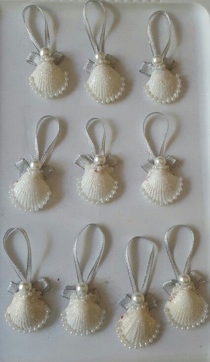 twelve white seashell ornaments with bows and pearls on the sides, all in different sizes