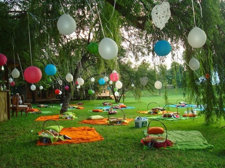 an outdoor party is set up in the grass with balloons and decorations hanging from the trees