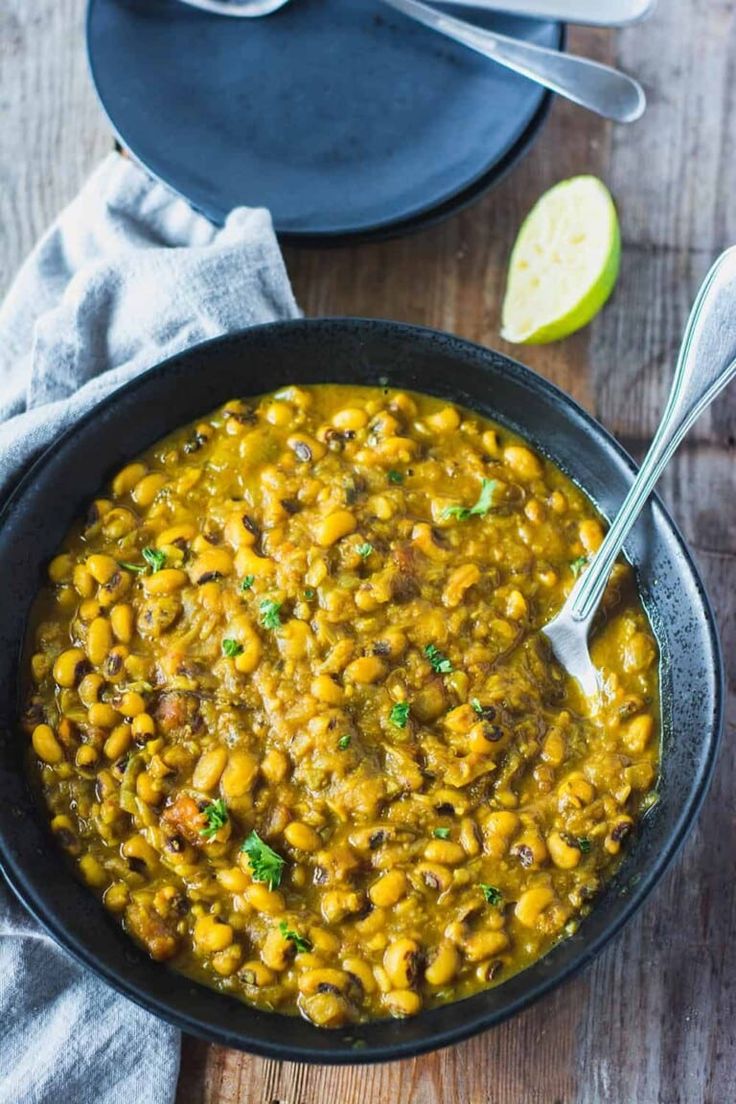 a bowl filled with beans and vegetables on top of a wooden table