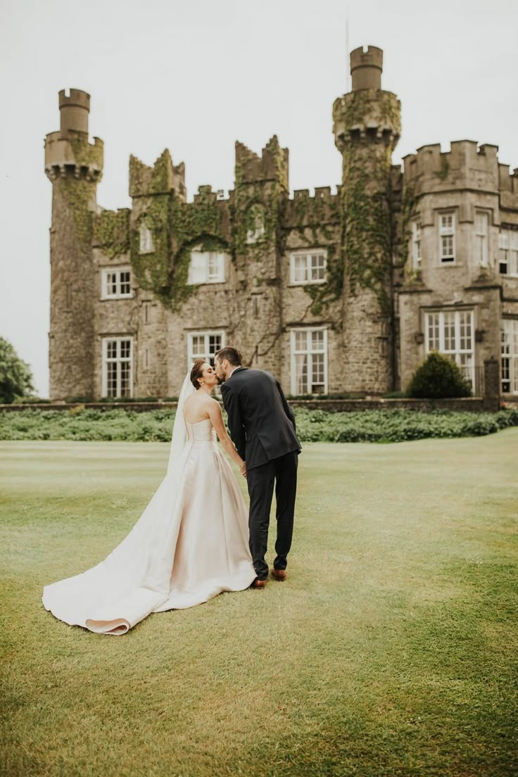 a bride and groom kissing in front of an old castle