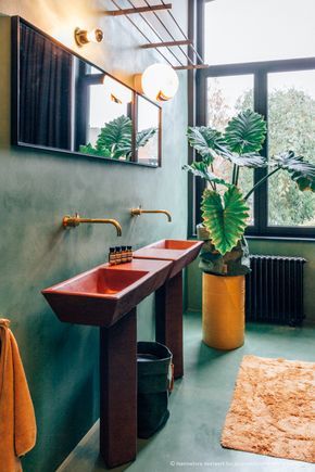 a bathroom with green walls and a red sink in the middle, next to a large window