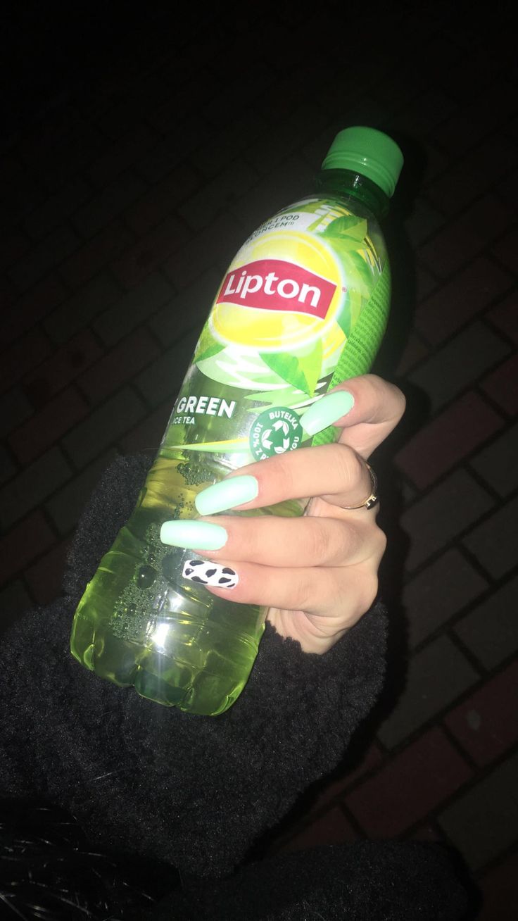 a woman holding up a bottle of green liquid