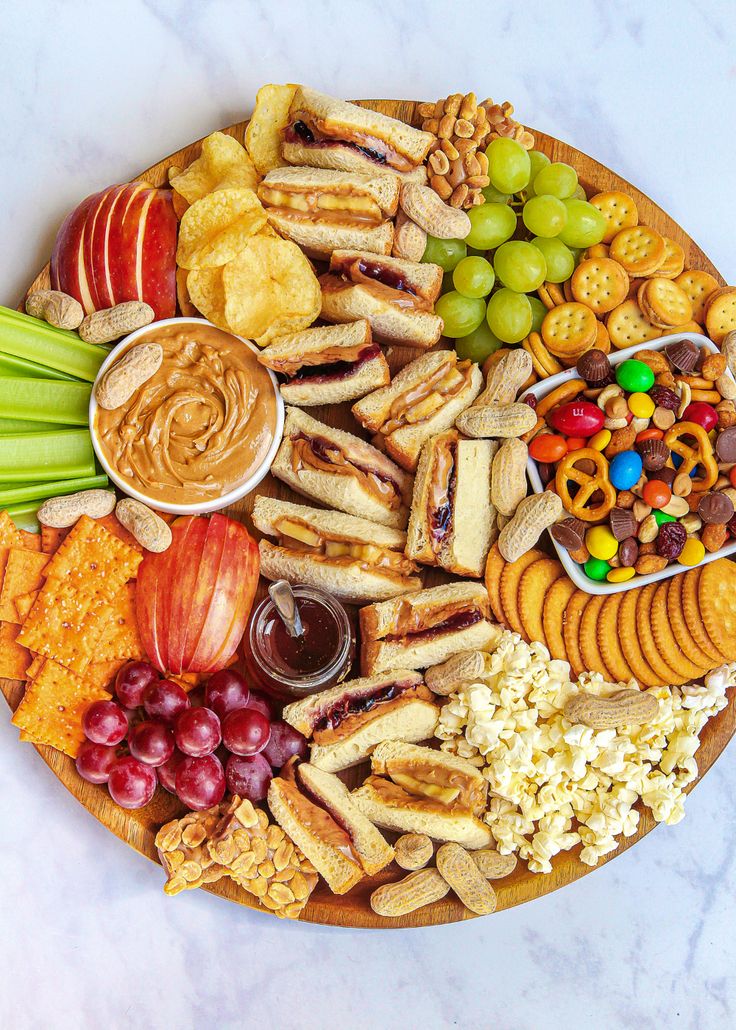 a platter filled with crackers, fruit and snacks