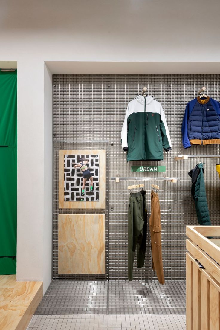 the inside of a clothing store with clothes on racks and coats hanging up against the wall