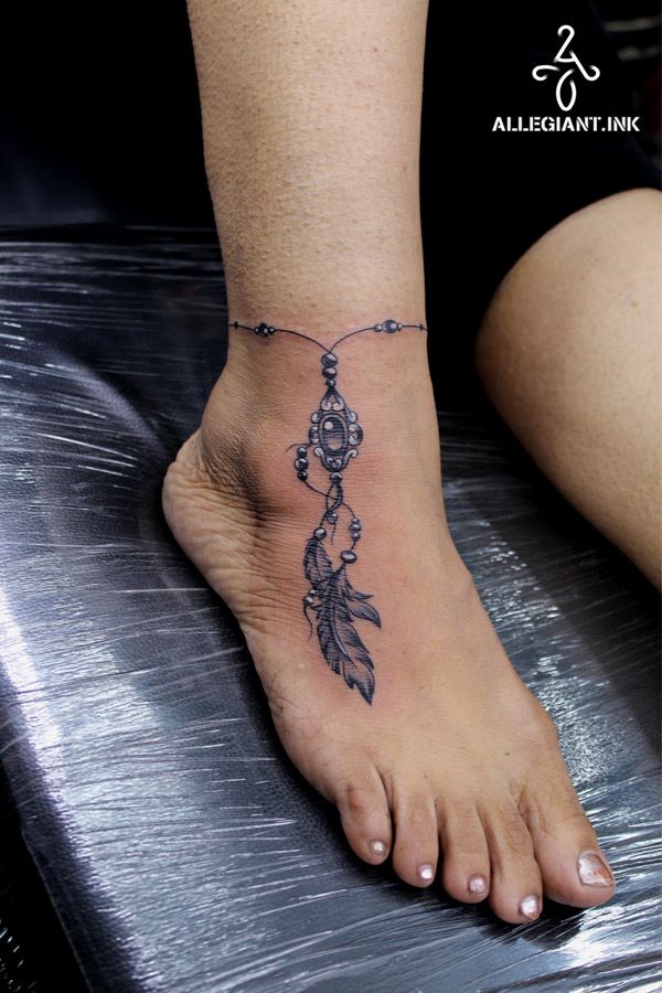 a woman's foot with a tattoo design on it and a chain hanging from the ankle