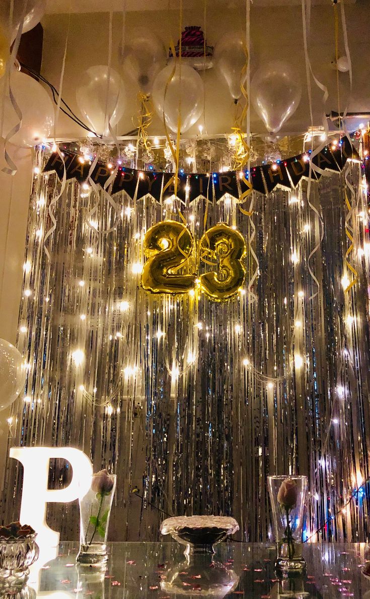 balloons and streamers are hanging from the ceiling in front of a party backdrop that reads 25