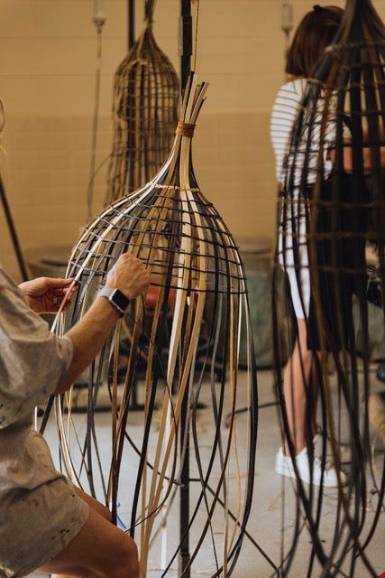 two people working on some kind of birdcage