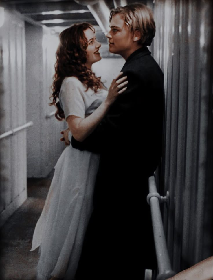 a man and woman standing next to each other in a hallway with curtains on the wall